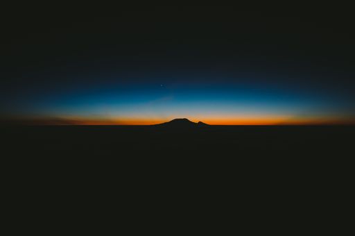 A beautiful shot of dark hills with the amazing orange and blue sunset on the horizon
