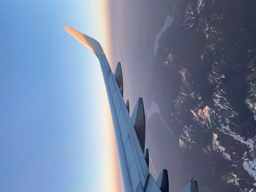 The sunrise over the snow-covered rocky mountains seen from above while flying home