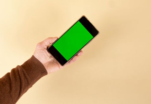 A person holding a smartphone with green screen