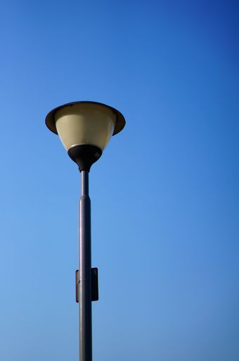 A low angle shot of an electric street lamp under a clear blue sky