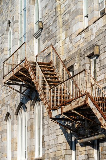 A vertical shot of a building exterior with outdoor rusty stairs