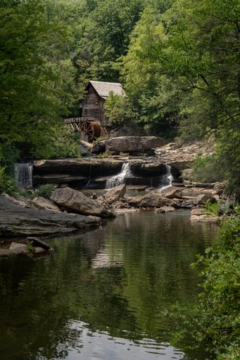 A scenic forest mill by rocks and waterfall