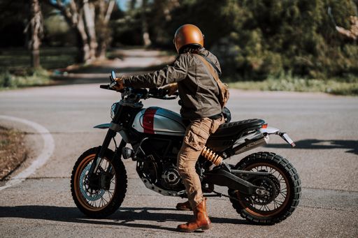 Man in helmet stands by motorcycle on urban street