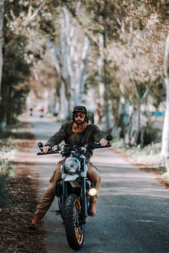 Man on motorbike rides through autumn forest on a road