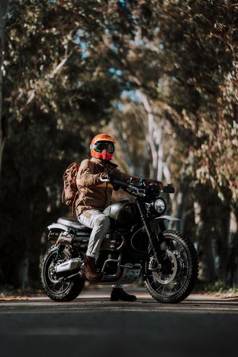 A person in a brown jacket riding a motorcycle