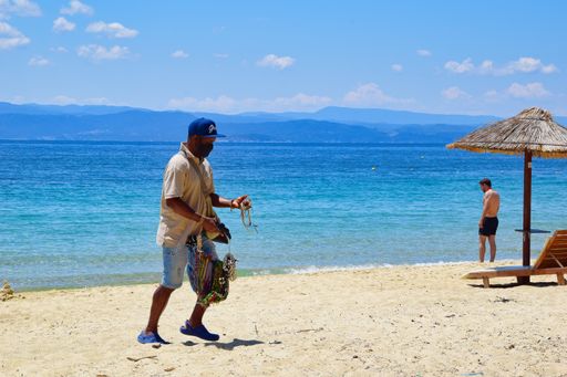 summer 2021, peddler sells handmade jewelry, Koukounaries beach, Skiathos, Greece,  6-13-2021