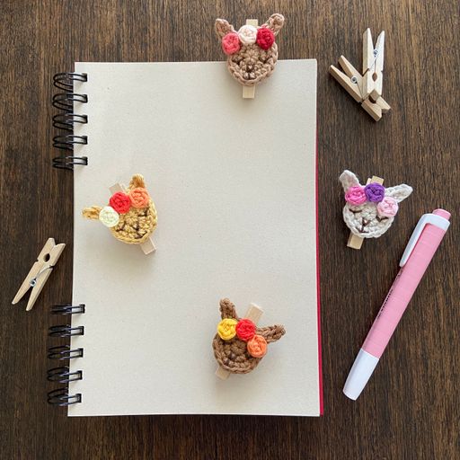 A top view of a blank notepad with space for text on the table with brooches and pins on it