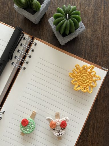A vertical shot of a blank notepad with space for text on the table with brooches and pins on it