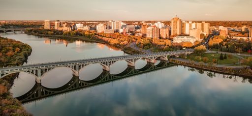 An aerial of a bridge over the Saskatchewan River with the city in the background in Saskatoon, SK, Canada