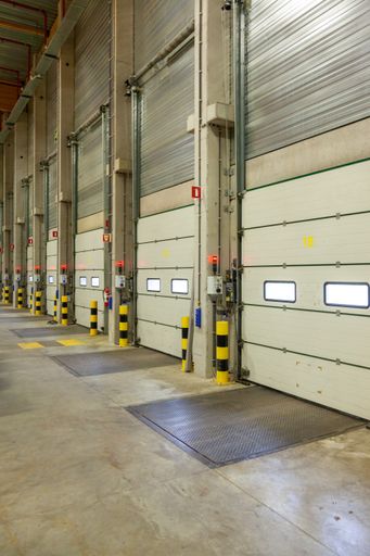 A vertical interior shot of a warehouse with a row of doors and control panels next to it