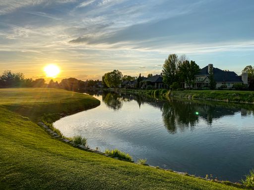 A scenic view of a calm river in the countryside with a bright sunset