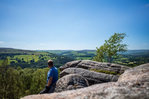 A man leaning on rocks enjoying the green nature up the hill in spring