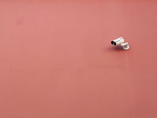 A surveillance security outdoor camera on an orange wall