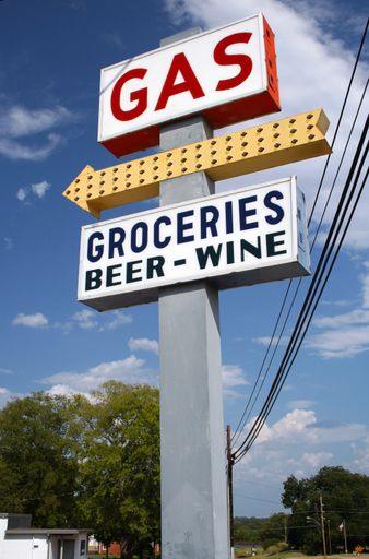 A vertical shot of a gas station sign under a blue sky