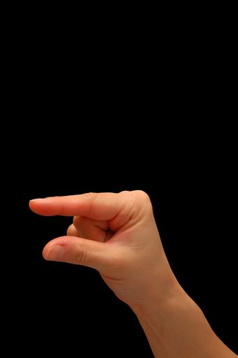 A closeup of a small hand gesture isolated on a black background with free space for text