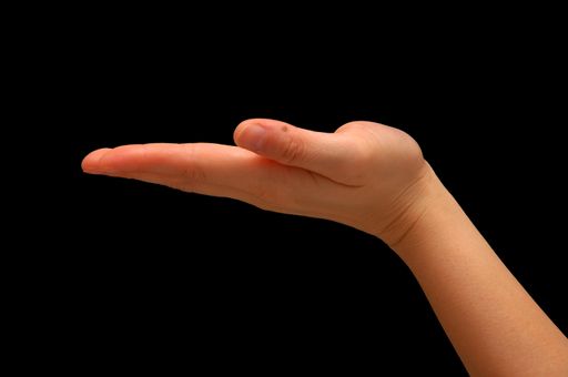 A closeup of an outstretched hand signaling " in support of something" isolated on a black background with free space for text