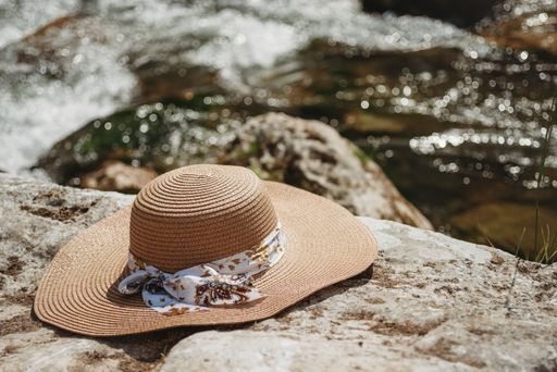 A closeup shot of beach straw hat on the rock by the river