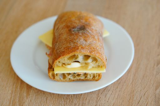 A closeup shot of bread with cheese in a white plate on a wooden table