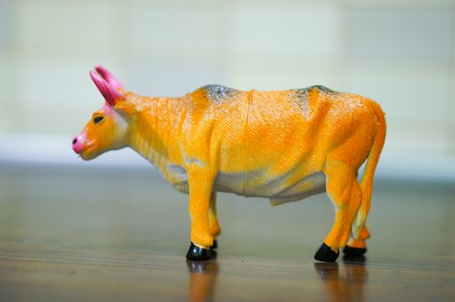 A closeup shot of a plastic toy bull on a wooden surface