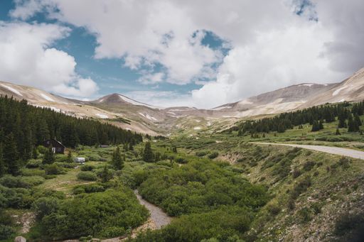 A scenic view of Colorado mountain valley with a ridge in the spring with a dirt road and creek