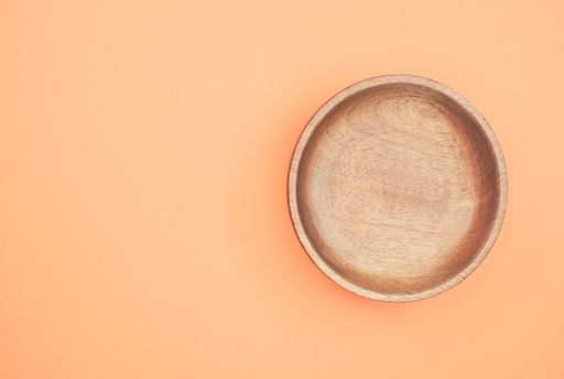 A top view of a wooden round tray on an orange background