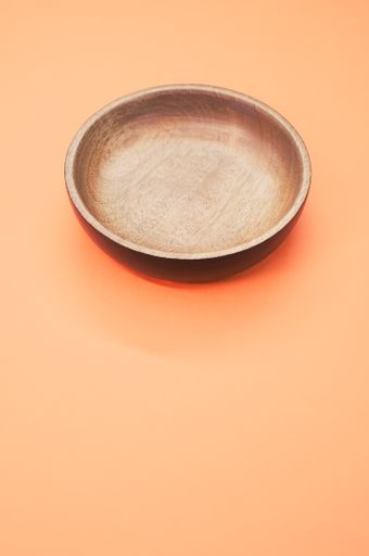 A top view of a wooden round tray on an orange background