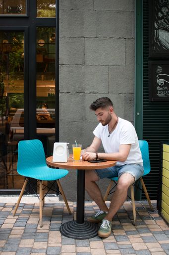 A bearded Armenian man with a white t-shirt writing in his notepad in an outdoor cafe
