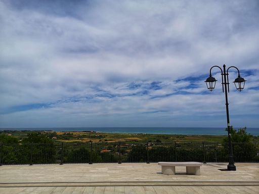 A scenic view of an empty bench and a street lamp in a park in Campomarino, Molise, Italy