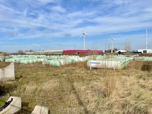 Storage area of gas tanks in an industrial area with clean energy wind turbines in the background. Location is the city of Zutphen in the Netherlands.