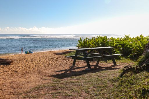 A picnic table sits beside the water at Kauai's Kephui Beach.
