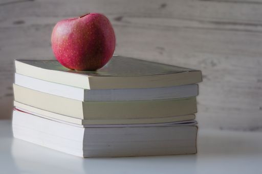 Red apple on top of a pile of books