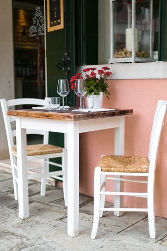 A dining table with chairs and a vase of flowers near a building.