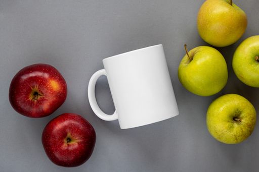 A top view of fresh green and red apples with a white mug in the middle isolated on a gray background