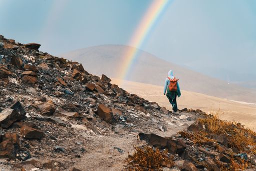 Wandering through the Unknown: An Anonymous Traveler's Journey Across Treacherous Mountain Paths into the Valley beneath the Arc of a Rainbow