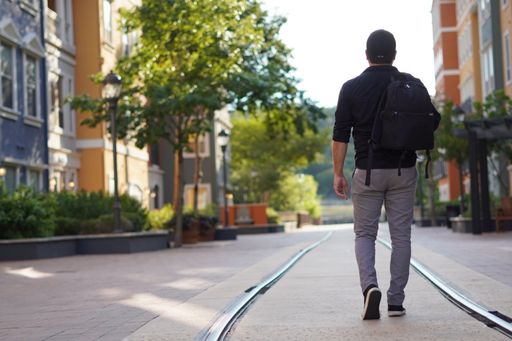 A man with a backpack strolling on street railway
