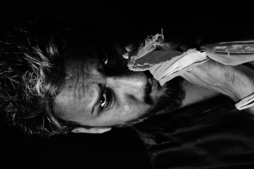 A grayscale portrait of an angry man with hands on each other with fabric on it