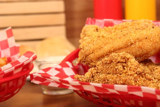 A closeup shot of french fries and fried catfish at a fast-food diner