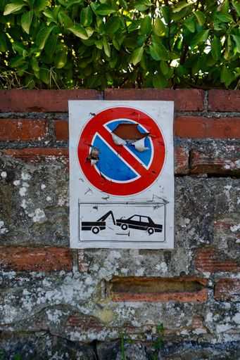 A vertical shot of rusty forbidding parking sign outdoor