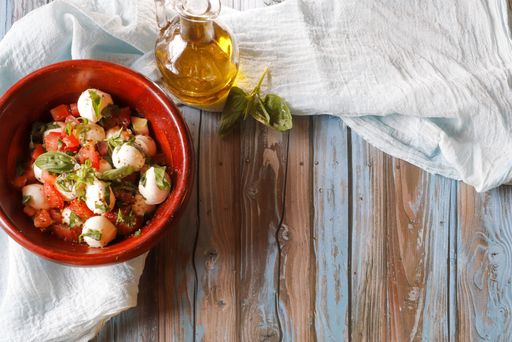 A top view shot of a salad made of vegetables and egg in a ceramic bowl on a wooden table