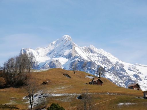 A scenic view of small houses on a hill with a snow-capped mountain in the background
