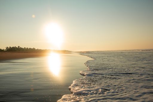 A view of foamy sea waves rushing into the sandy shore at dawn