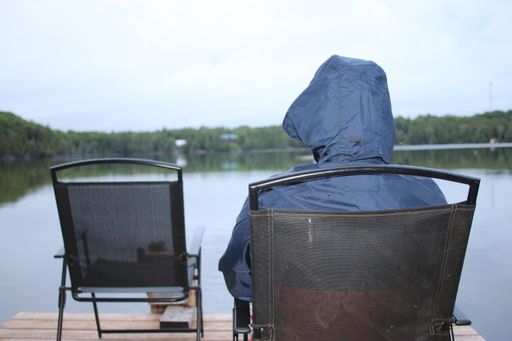 A person sitting on a chair by a lake and catching fish