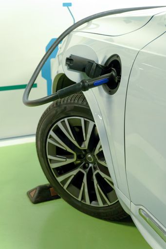 white electric car connected to the grid at a charging station in a public garage