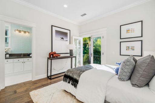 A modern bedroom with white walls, windows, and hardwood floors
