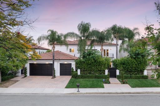 A driveway leading to a house with palm trees at sunset