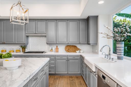A spacious modern kitchen with marble countertops, cabinets, and hardwood floors