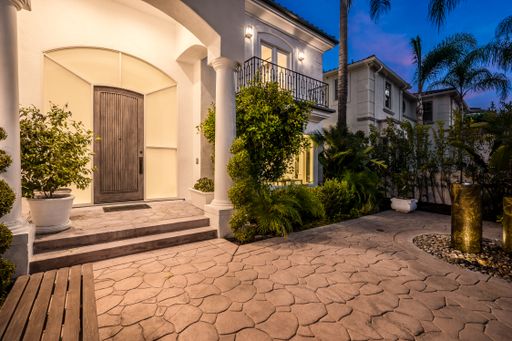 An illuminated stone path and stairs leading to a house entrance at sunset