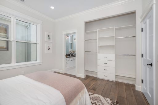 A modern bedroom with hardwood floors, a bed, and a closet space