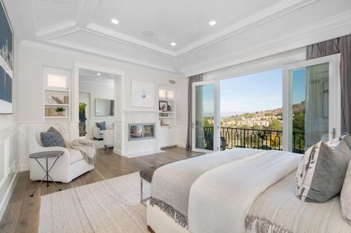 A large bedroom with a balcony featuring a spacious bed