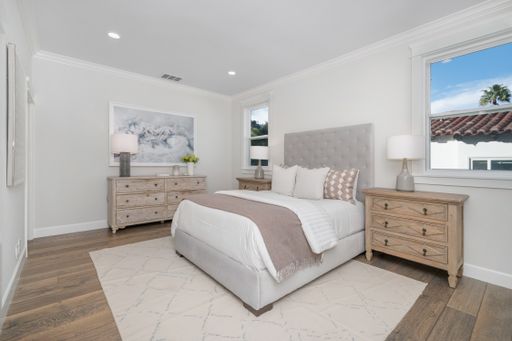 A tidy bedroom with a well-made bed and dressers in the corner